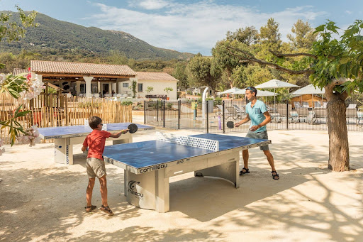 Kinderen spelen tafeltennis op een vakantieverblijf in Corsica met bergen en natuur op de achtergrond